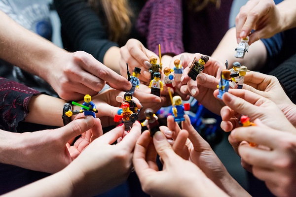 A circle of people hold Lego figures.