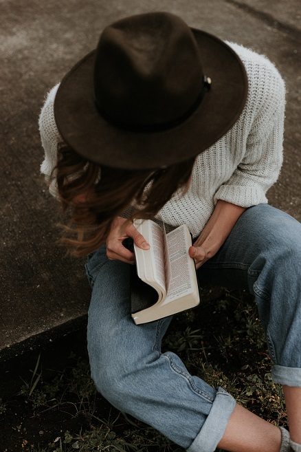 Une femme assise avec une Bible dans ses mains.