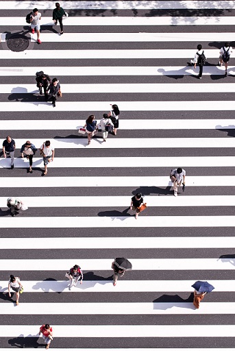 A crosswalk, viewed from above.  A number of people are crossing.